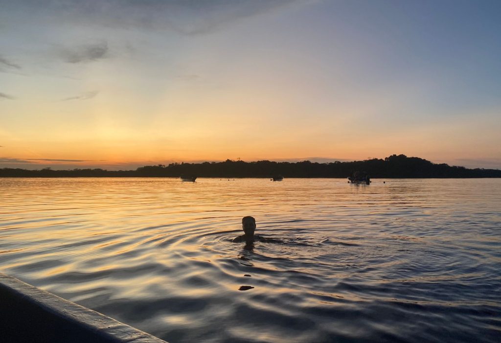 Woman swimming in the Amazon river in Ecuador at sunset
