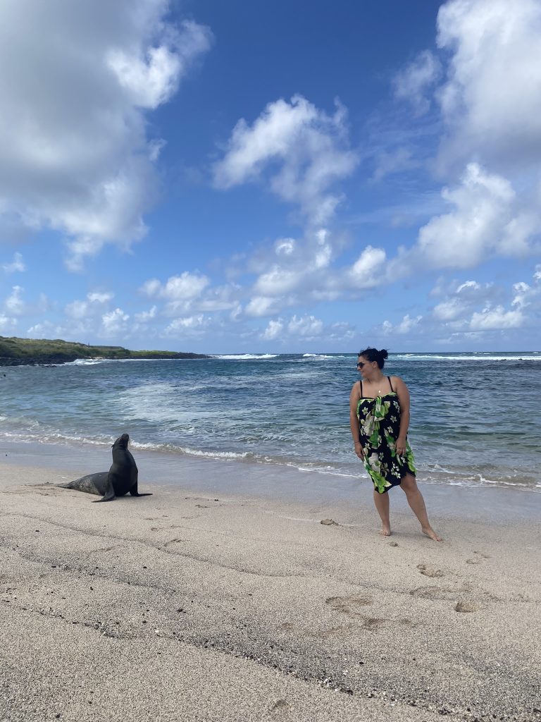 A woman stood on a beach next to a sea lion in the Galapagos Islands, Ecuador.