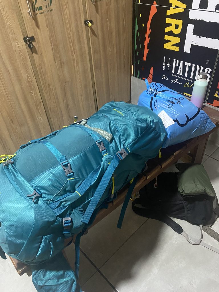 A backpack and other luggage laid on a bench.